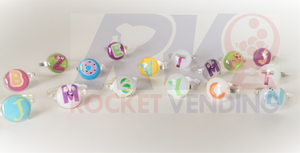 Anillos Letras Para Niñas Metal Juguete Encapsulado 1 pulgada 100 Pzas 1p - Rocket Vending Todo en Chicleras